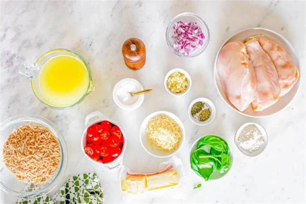 Ingredients for crockpot Italian chicken and orzo including chicken breasts, Italian dressing, chicken broth, Parmesan cheese, garlic, herbs, and uncooked orzo.