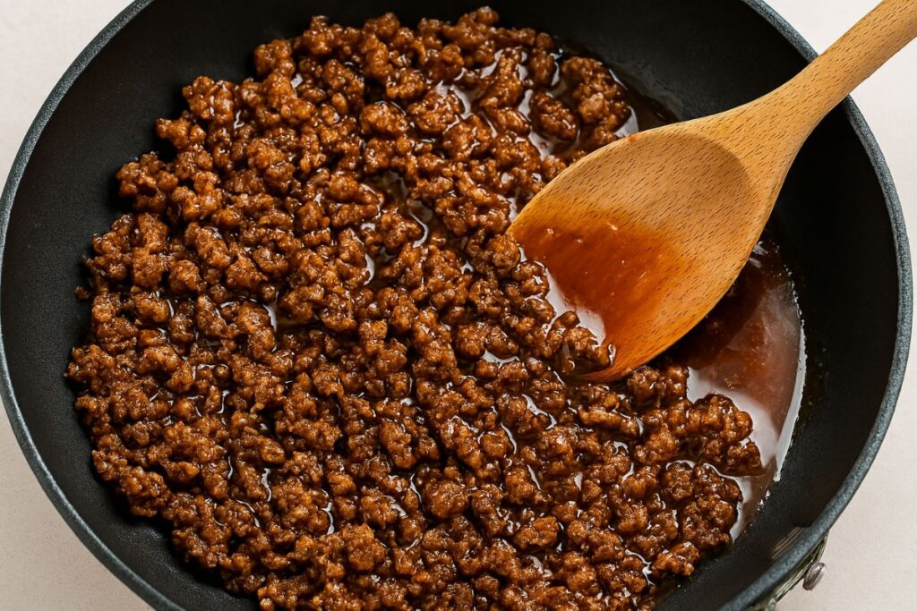 Beef cooking with hot honey glaze in a skillet