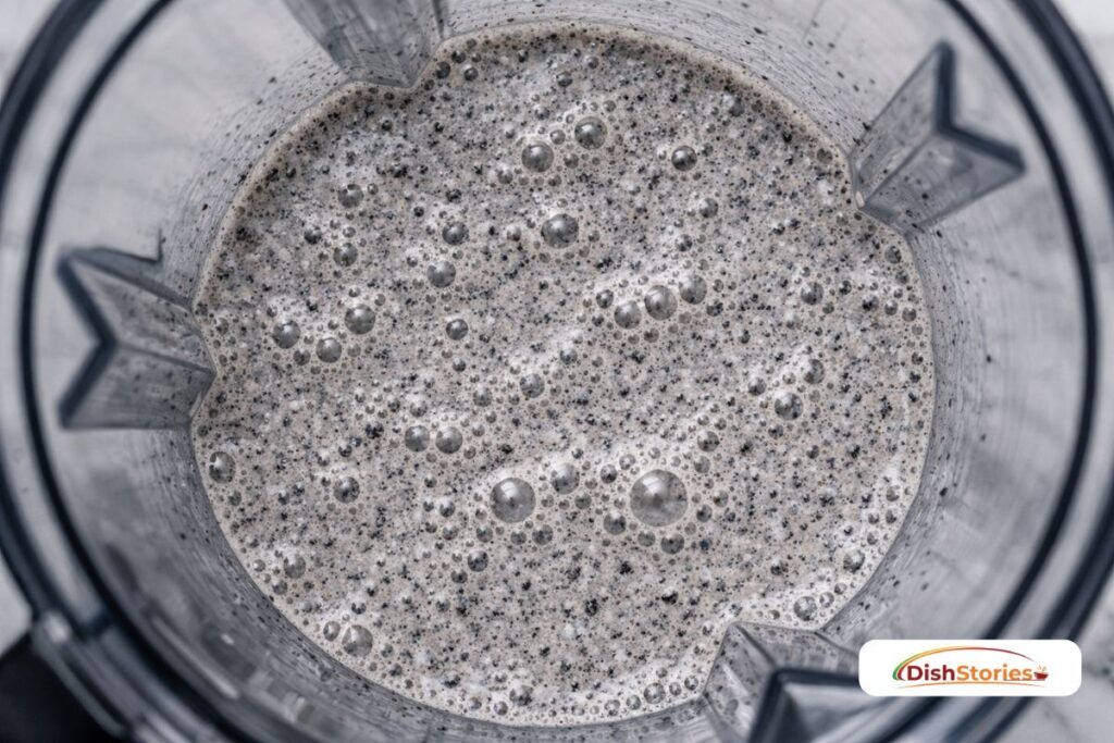 Pulverized Oreo cookies mixed with milk in a blender jar to create a deep cocoa flavor base.