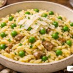 A glistening bowl of garlic butter orzo with bright green peas and shaved parmesan