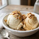 Creamy scoop of homemade dairy free ice cream without machine in a white bowl with toasted almonds