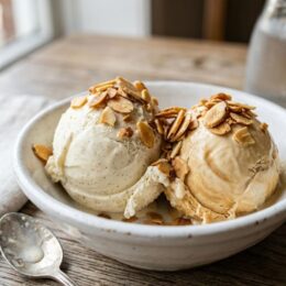 Creamy scoop of homemade dairy free ice cream without machine in a white bowl with toasted almonds
