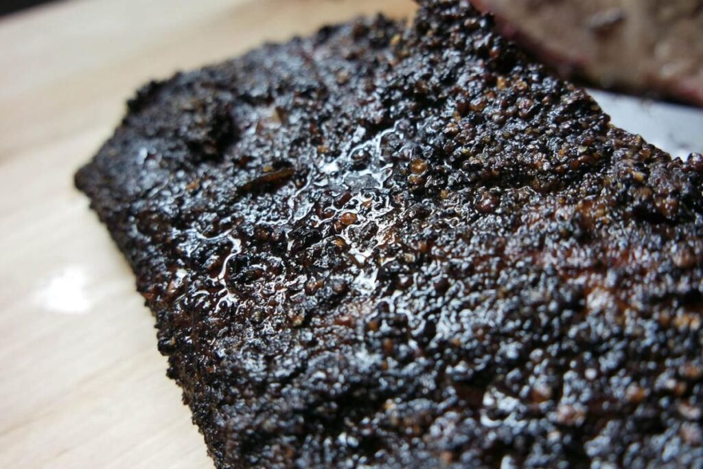 Close-up of perfectly smoked beef brisket bark with a dark, crusty exterior and visible smoke ring, showing ideal Texas-style barbecue texture.